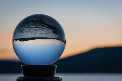 Close-up of crystal ball against sky during sunset