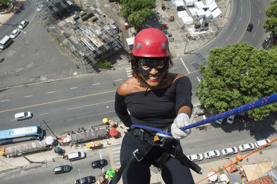 A woman wearing a hero costume with protective helmet walking down a tall rappel building. 