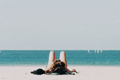 Woman lying on beach against sky