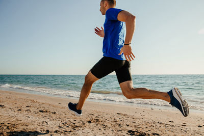 Man running on beach against clear sky