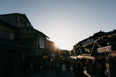 People on street amidst buildings against clear sky