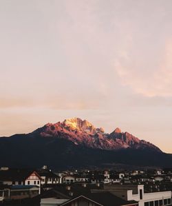 Town by mountain against sky during sunset