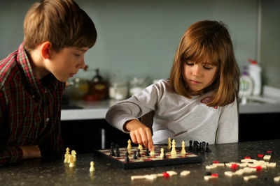 Children playing chess at home kitchen