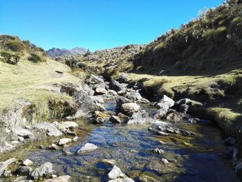 Scenic view of river by mountains against clear sky