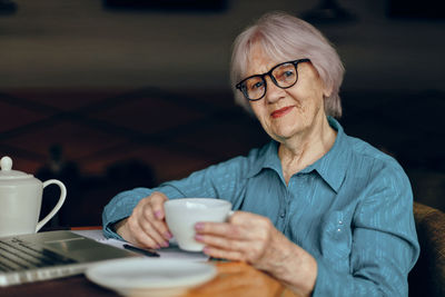 Portrait of young woman using mobile phone at home