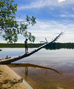 Side view of person on lake against sky