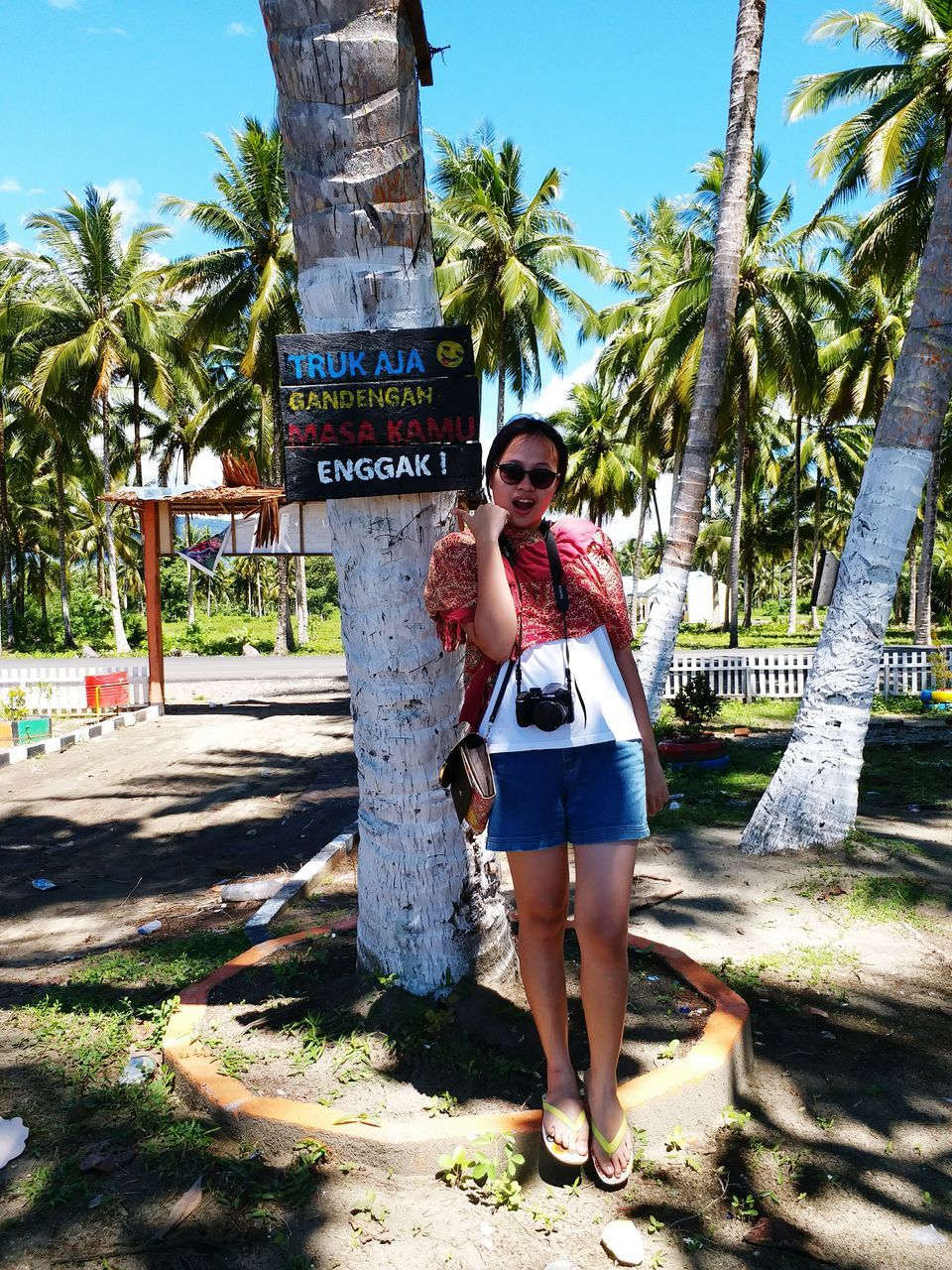 FULL LENGTH OF HAPPY YOUNG WOMAN STANDING AGAINST TREES