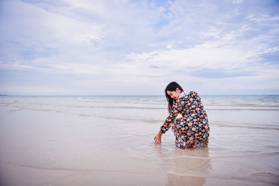 Woman with umbrella on beach against sky