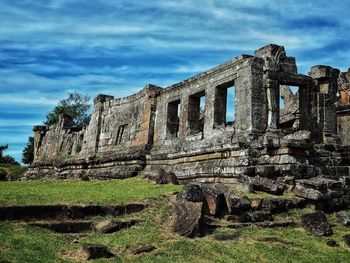 Low angle view of abandoned building against cloudy sky