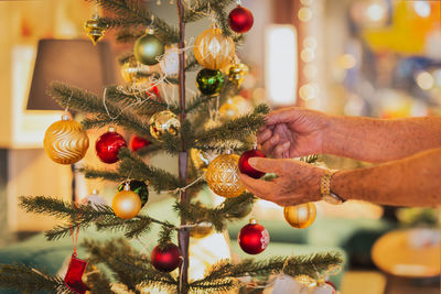 Senior man decorating a christmas tree at home.