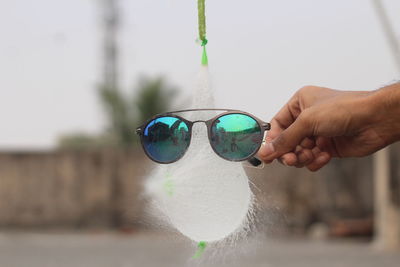 Close-up of hand holding sunglasses against blurred background