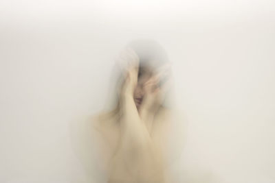 Midsection of woman covering face against white background