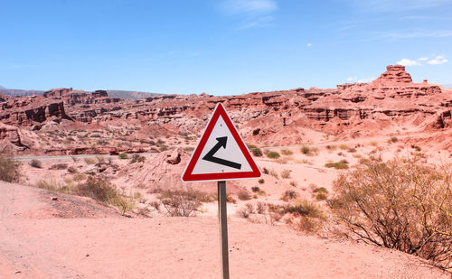 Road sign in desert against sky