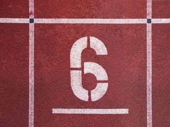 Number six. white athletic track number on red rubber racetrack, texture of racetracks in stadium