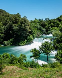 Scenic view of waterfall amidst trees in forest against sky