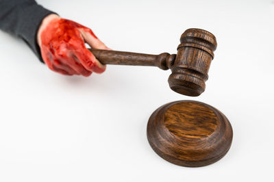 Cropped hand of man holding hammer against white background