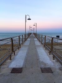 Pier on sea against sky during sunset