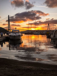 Sailboats moored on sea against sky during sunset