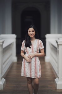 Portrait of smiling young woman standing in corridor