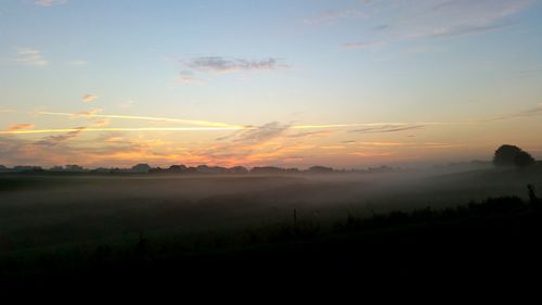 Scenic view of silhouette field against sky during sunset