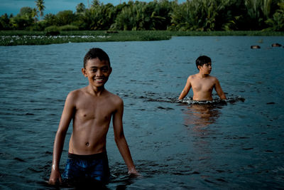 Full length of shirtless boy standing in water