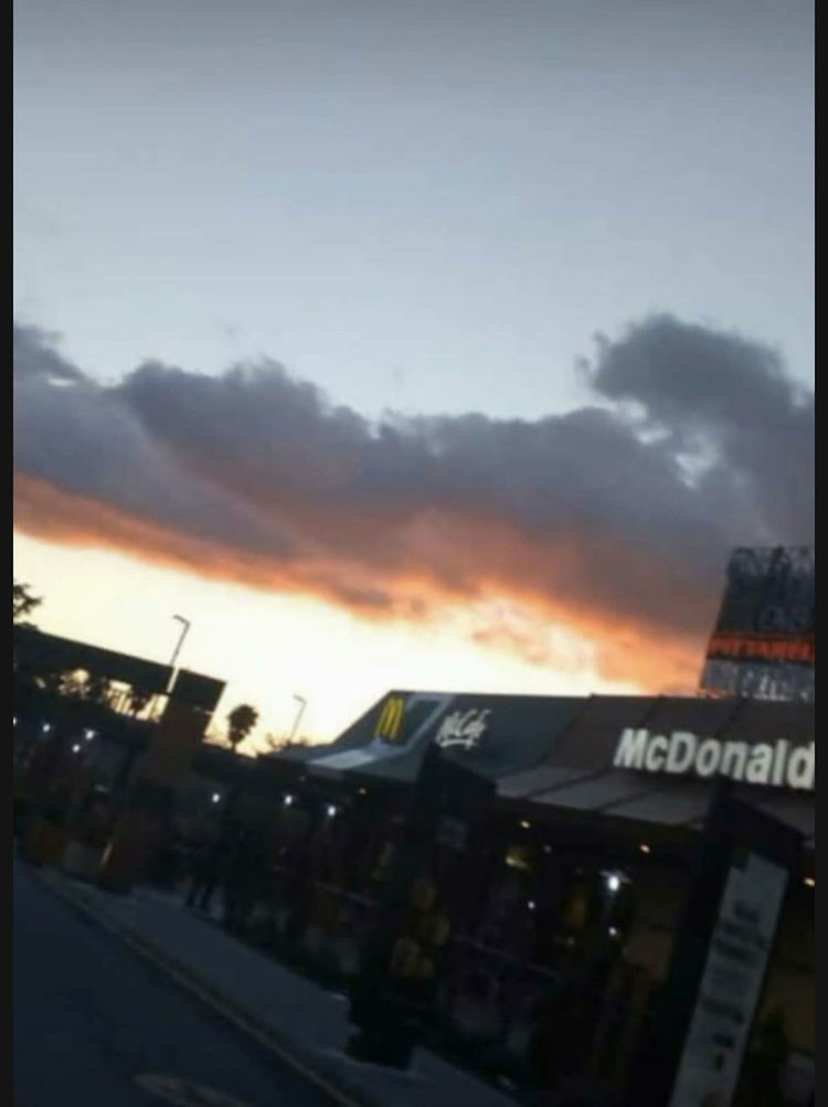 CARS ON STREET BY BUILDINGS AGAINST SKY AT SUNSET