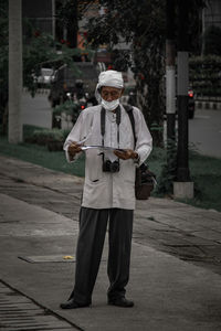 Full length portrait of man standing on footpath