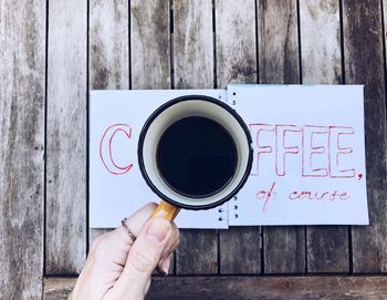 Directly above shot of hand holding coffee cup on table