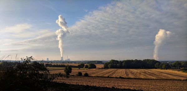 Smoke emitting from chimney on field against sky