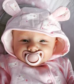 Portrait of cute baby girl lying on bed at home