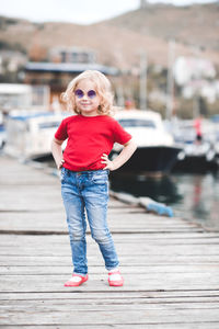 Smiling girl with sunglasses standing on jetty