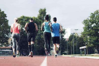 Rear view of athletes running on track