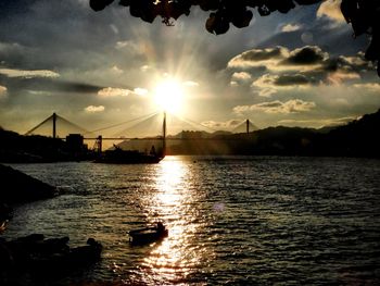 Silhouette bridge over sea against sky during sunset