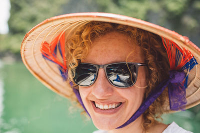Close-up portrait of smiling woman wearing sunglasses and hat