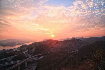 Scenic view of landscape against dramatic sky at sunset