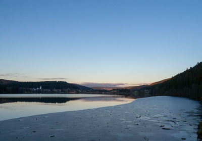 Scenic view of lake against clear blue sky during winter
