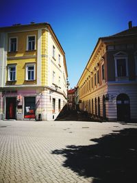 Street amidst buildings in town against blue sky