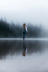 Young person standing in the foggy lake near the wilderness forest. lifestyle,hipster style.	