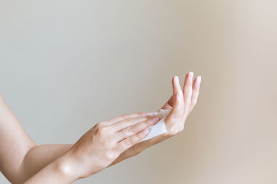 Cropped hands of woman holding tissue paper against white background