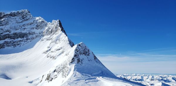 Snow covered mountain against blue sky