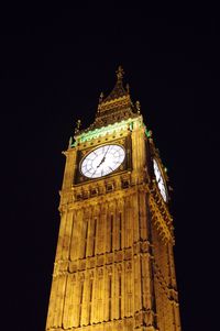 Low angle view of clock tower at night