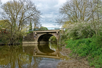 Arch bridge over river against sky