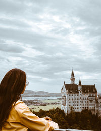Rear view of woman looking at buildings against sky