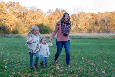 Full length portrait of smiling girl standing on plants during autumn