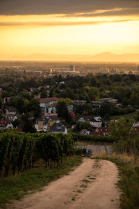 Road by townscape against sky during sunset