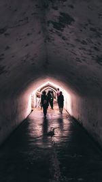 Rear view of people walking in tunnel