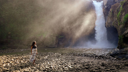 Woman standing in waterfall