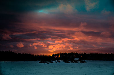 Silhouette landscape against dramatic sky during sunset