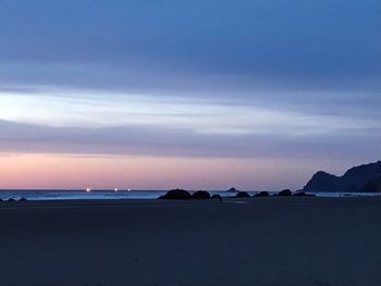 Scenic view of beach against sky at sunset