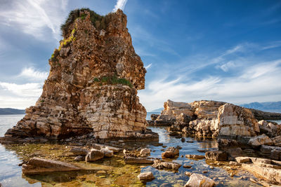 Rock formation on shore against sky